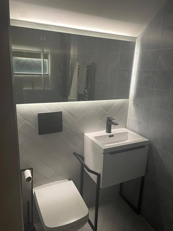 Finished cloakroom side angle showing frame-leg basin and herringbone tile detail