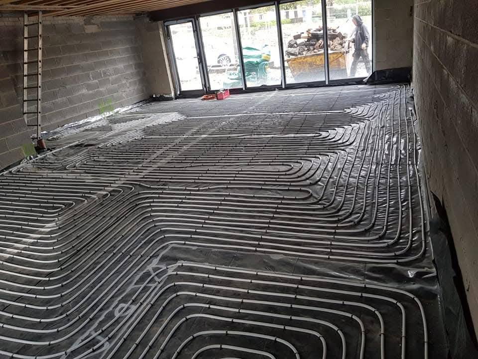 PEX underfloor heating pipework laid in a snaking pattern across a ground floor, ready for screed in a new build